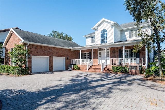 view of front of house with a garage, decorative driveway, brick siding, and a porch