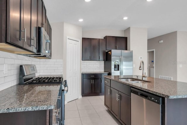 kitchen featuring stainless steel appliances, visible vents, a sink, dark stone countertops, and dark brown cabinets