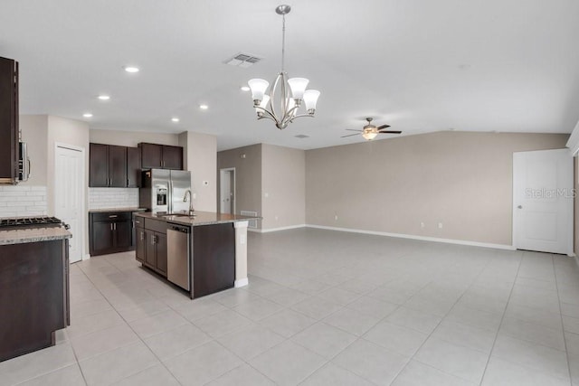 kitchen with stainless steel appliances, decorative backsplash, open floor plan, dark brown cabinetry, and ceiling fan with notable chandelier