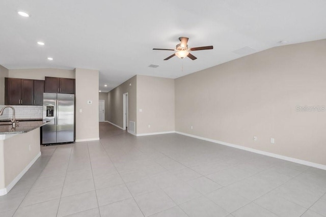 interior space with stone counters, a sink, dark brown cabinets, decorative backsplash, and stainless steel fridge