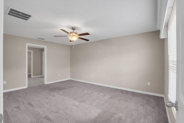 carpeted empty room featuring a ceiling fan, visible vents, and baseboards