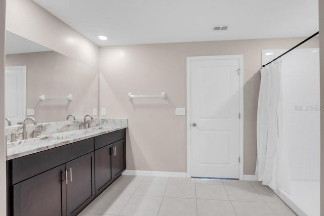 full bathroom featuring double vanity, baseboards, a sink, and tile patterned floors