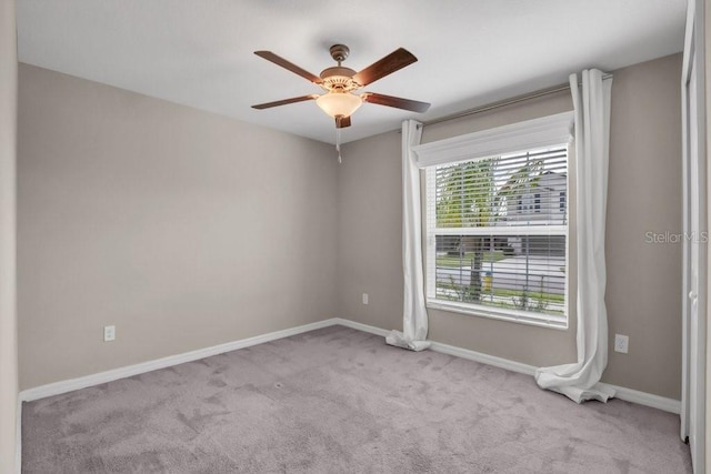 carpeted spare room with baseboards and a ceiling fan