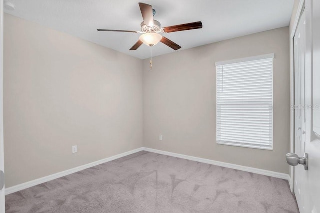 carpeted spare room featuring ceiling fan and baseboards