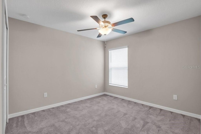 carpeted empty room with baseboards and a ceiling fan