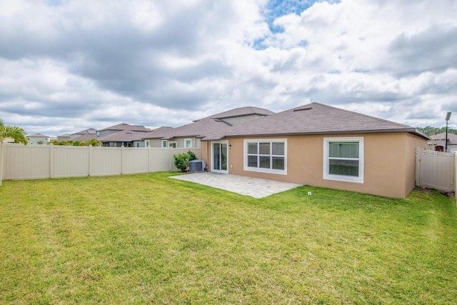 rear view of house featuring stucco siding, a lawn, a patio area, cooling unit, and a fenced backyard