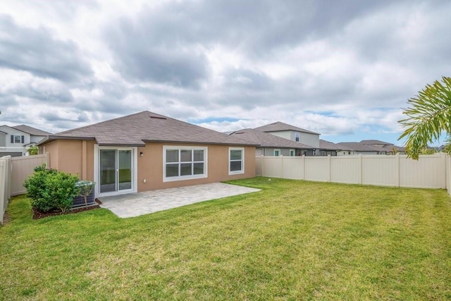 back of property with a fenced backyard, a shingled roof, a lawn, stucco siding, and a patio area