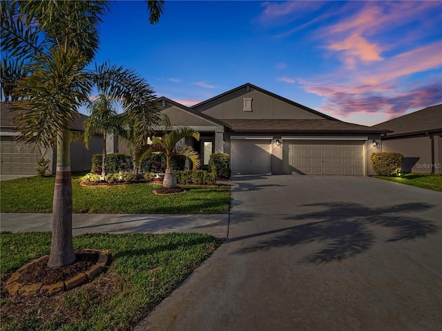 view of front of property featuring a garage, a front yard, driveway, and stucco siding