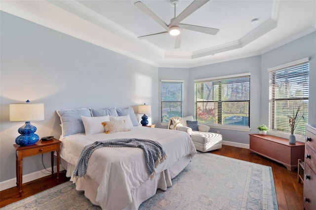 bedroom featuring baseboards, a raised ceiling, a ceiling fan, dark wood finished floors, and ornamental molding