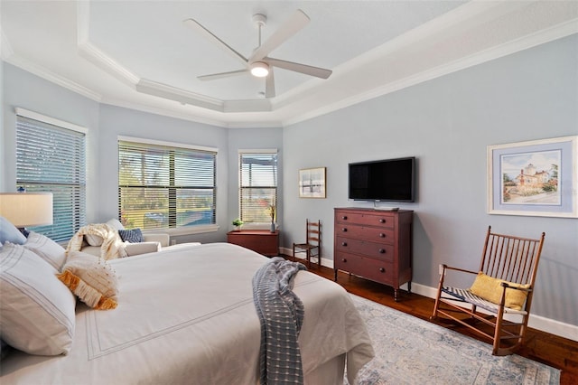 bedroom with ornamental molding, a raised ceiling, baseboards, and wood finished floors