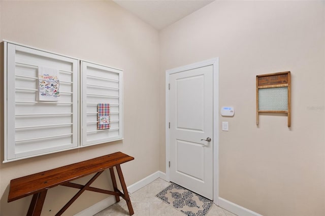 doorway with light tile patterned flooring and baseboards