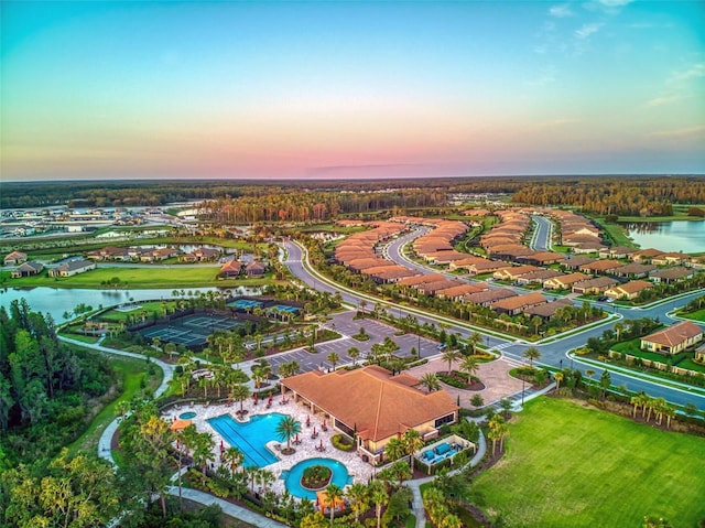 aerial view at dusk with a water view and a residential view