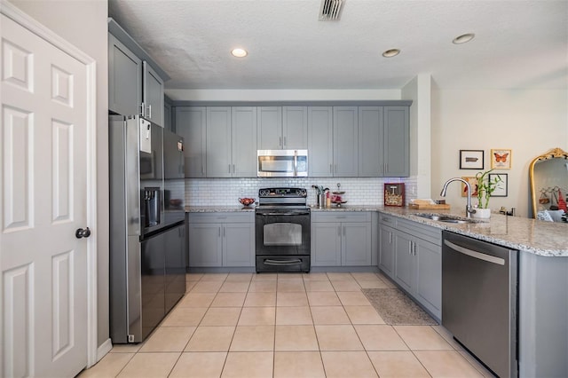 kitchen with black appliances, a peninsula, a sink, and gray cabinetry