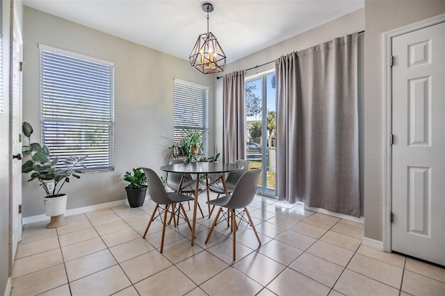 dining space with an inviting chandelier, baseboards, and light tile patterned floors