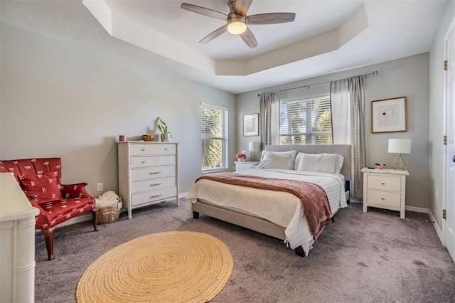 bedroom with carpet flooring, a raised ceiling, a ceiling fan, and baseboards