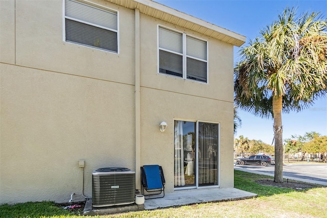 rear view of property featuring stucco siding and central air condition unit