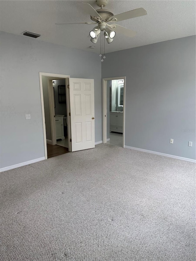 unfurnished bedroom featuring ensuite bathroom, baseboards, carpet floors, and a textured ceiling