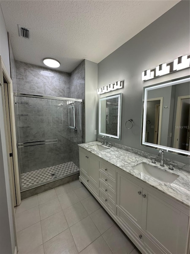 bathroom with double vanity, visible vents, a sink, and a stall shower