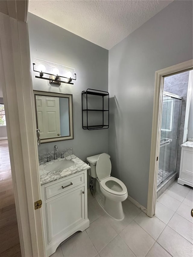 full bath featuring tile patterned flooring, vanity, a textured ceiling, and a stall shower