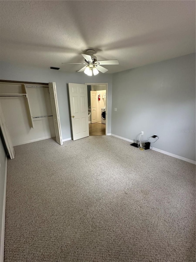 unfurnished bedroom with washer / clothes dryer, baseboards, a closet, carpet flooring, and a textured ceiling