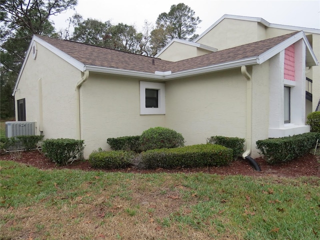 view of property exterior with a shingled roof, stucco siding, and central air condition unit