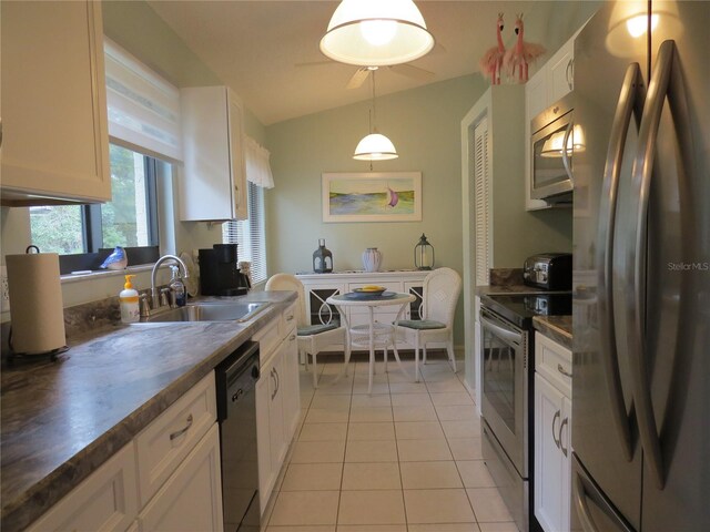 kitchen featuring decorative light fixtures, light tile patterned floors, stainless steel appliances, white cabinets, and a sink