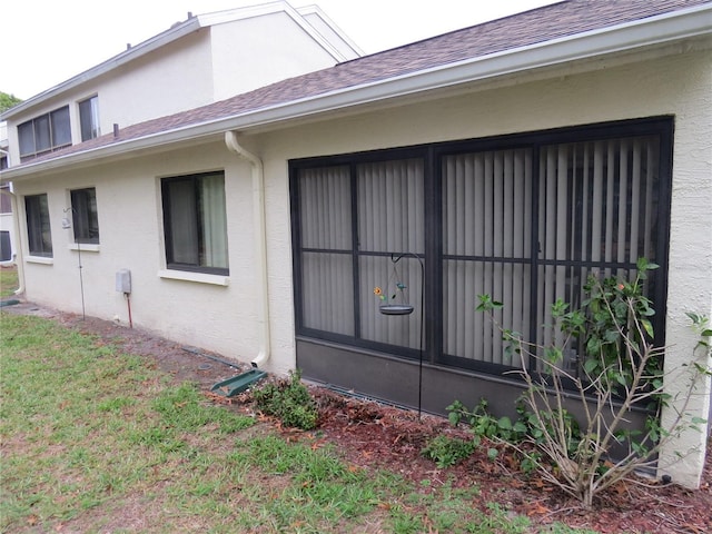 view of side of property with roof with shingles and stucco siding