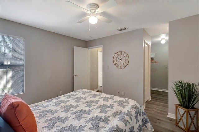 bedroom featuring baseboards, ceiling fan, visible vents, and wood finished floors