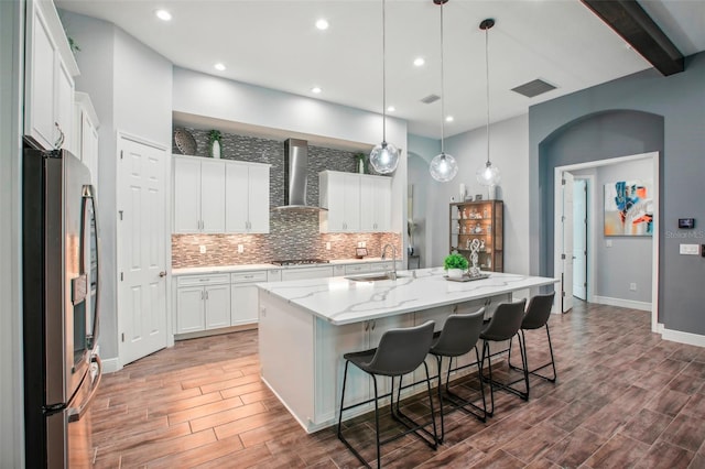 kitchen featuring a sink, stainless steel appliances, wall chimney exhaust hood, decorative backsplash, and wood tiled floor