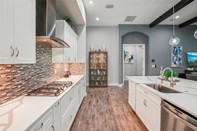 kitchen featuring light wood finished floors, a sink, decorative backsplash, stainless steel appliances, and wall chimney exhaust hood