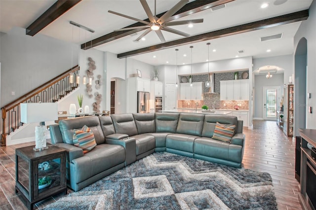 living room featuring stairway, visible vents, arched walkways, and wood finish floors