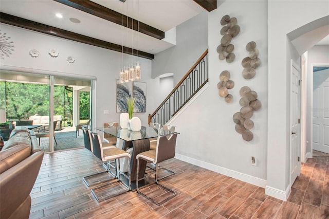 dining space with baseboards, wood tiled floor, beam ceiling, arched walkways, and a chandelier