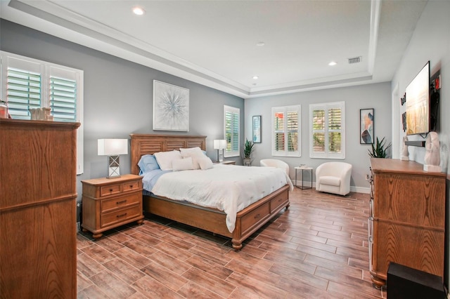 bedroom featuring visible vents, baseboards, a raised ceiling, and wood finish floors