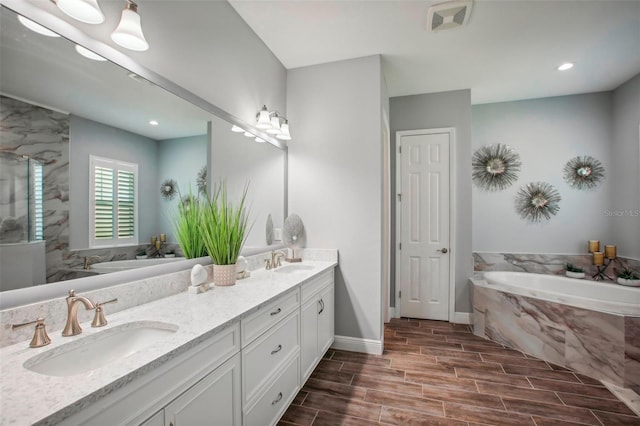 bathroom with a sink, a garden tub, double vanity, and wood tiled floor