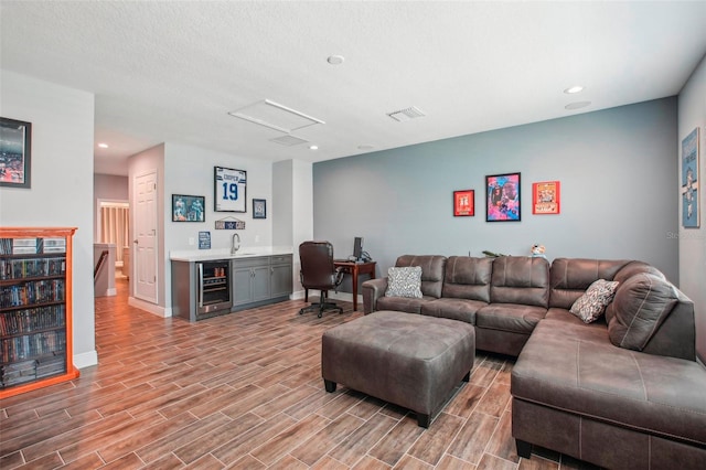 living area with beverage cooler, baseboards, visible vents, wood tiled floor, and wet bar