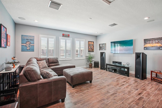 living room with baseboards, wood finished floors, visible vents, and a textured ceiling