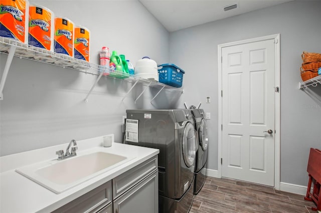 laundry area with visible vents, a sink, laundry area, wood tiled floor, and washing machine and clothes dryer