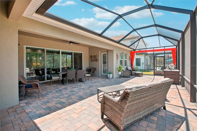 view of patio / terrace featuring an outdoor living space, glass enclosure, outdoor dining area, and a ceiling fan