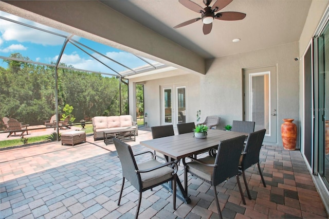 view of patio with outdoor dining area, an outdoor living space, glass enclosure, and a ceiling fan