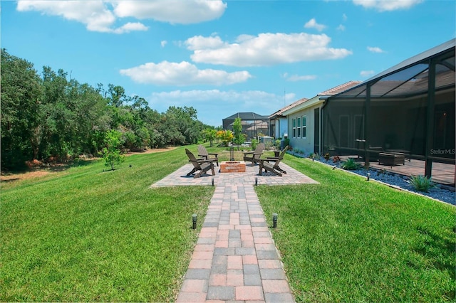 view of yard with glass enclosure, a patio, and an outdoor fire pit