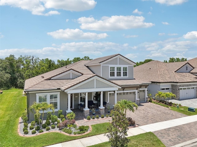 view of front of property featuring decorative driveway, a porch, a front yard, and a tile roof