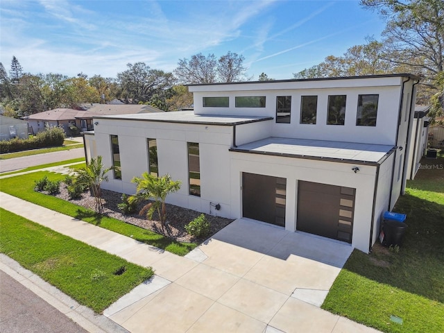 contemporary home with driveway, a garage, and stucco siding