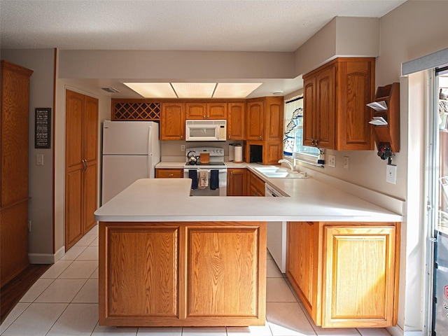 kitchen with light countertops, white appliances, light tile patterned flooring, and a sink