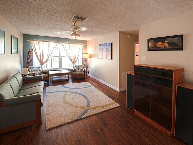 living room with a textured ceiling, wood finished floors, visible vents, and baseboards