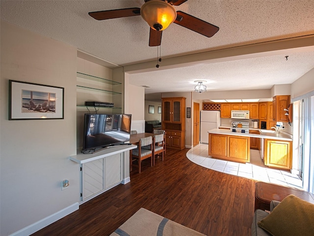 kitchen with a textured ceiling, white appliances, light countertops, light wood finished floors, and brown cabinetry