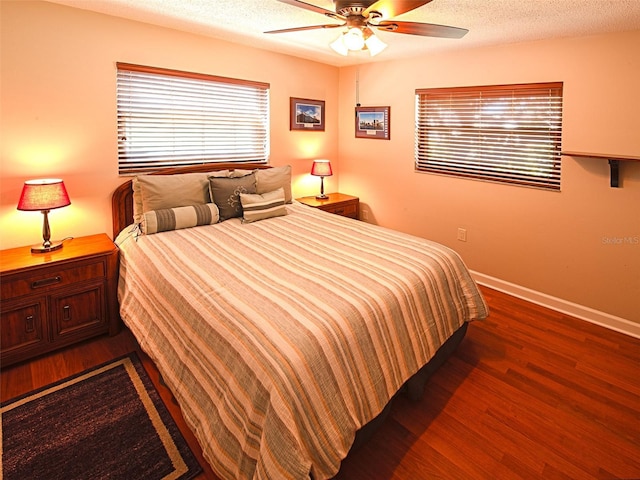 bedroom featuring a textured ceiling, multiple windows, wood finished floors, and baseboards