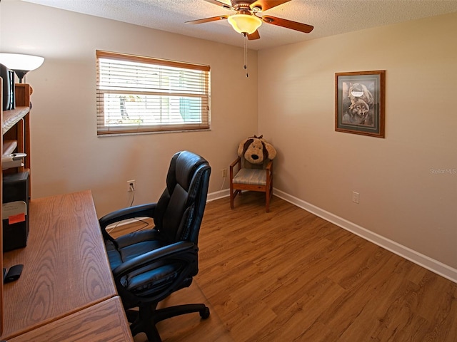 office space with ceiling fan, a textured ceiling, baseboards, and wood finished floors