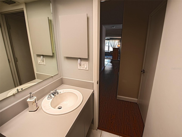 bathroom featuring visible vents, wood finished floors, vanity, and baseboards