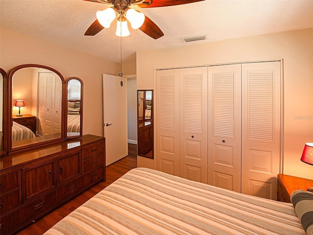 bedroom featuring visible vents, a ceiling fan, dark wood-type flooring, a textured ceiling, and a closet