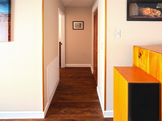 corridor with dark wood-style flooring, visible vents, and baseboards